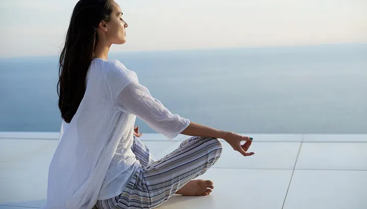 young woman practice yoga meditaion on sunset with ocean view in background