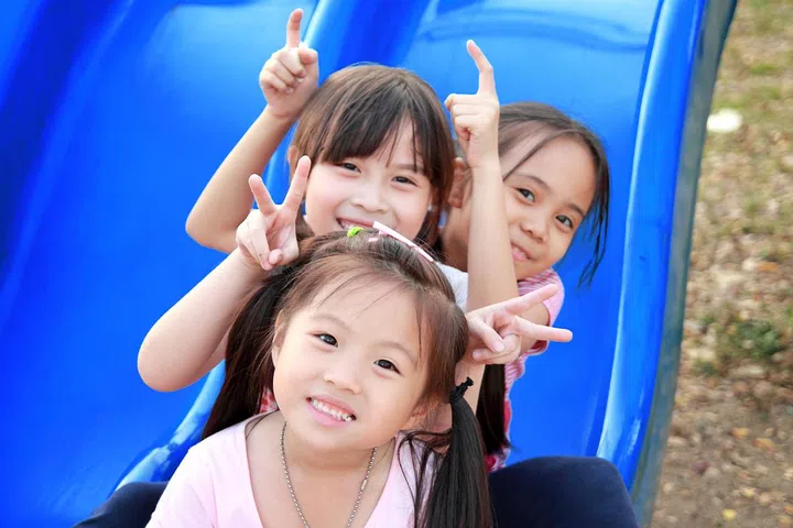 Three happy smiling children playing in park