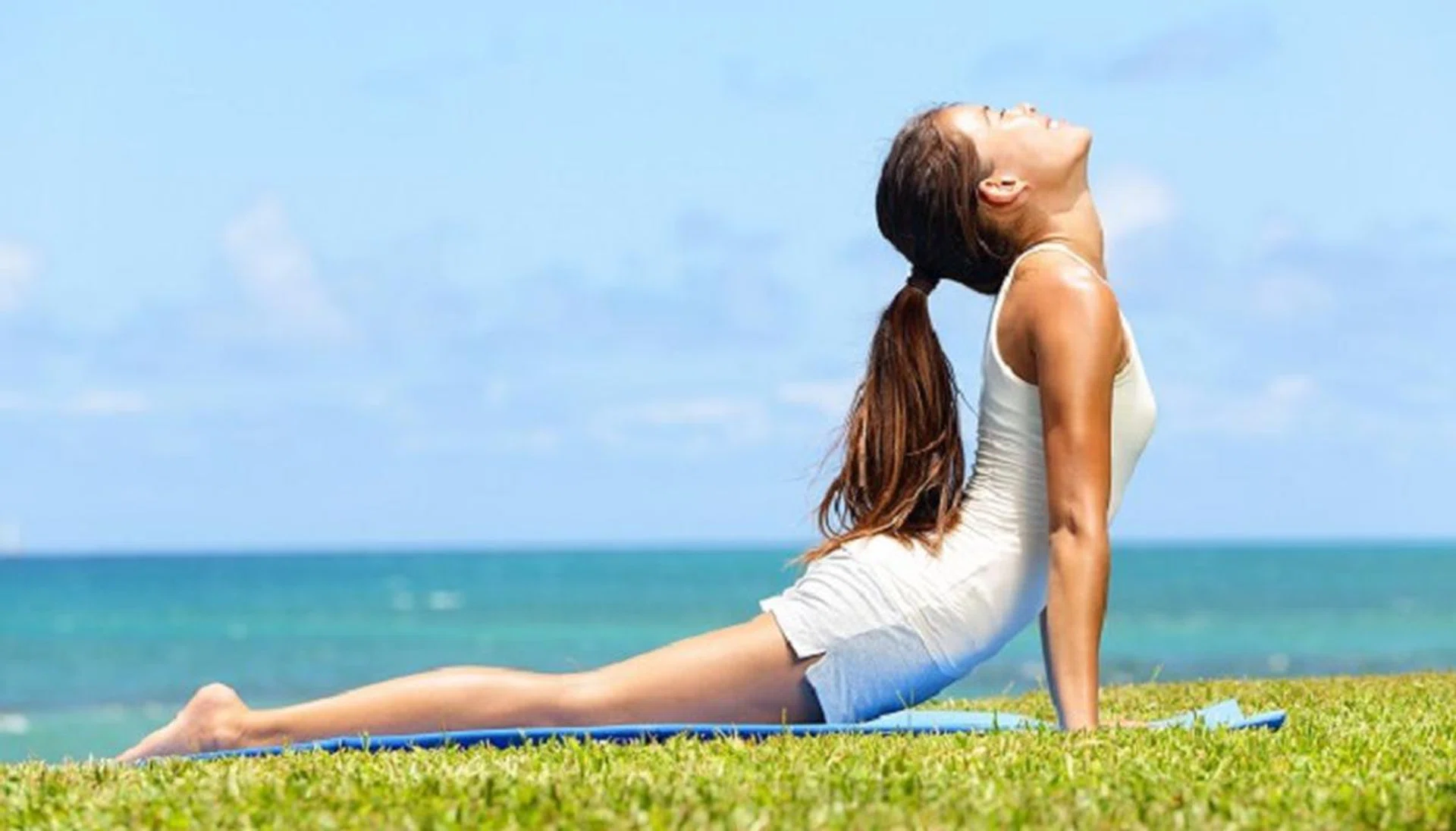 20560249 - fitness yoga woman stretching abdominal stomach muscles in cobra posture, bhujangasana. fit fitness girl stretching out after exercising outside on beach in summer. beautiful multiracial female model.