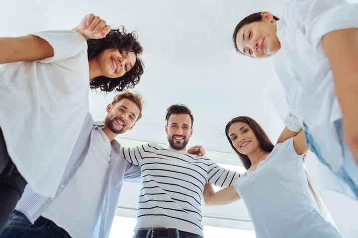 Pleasant cooperation. Joyful positive delighted team standing together and looking at you while being ready to work together