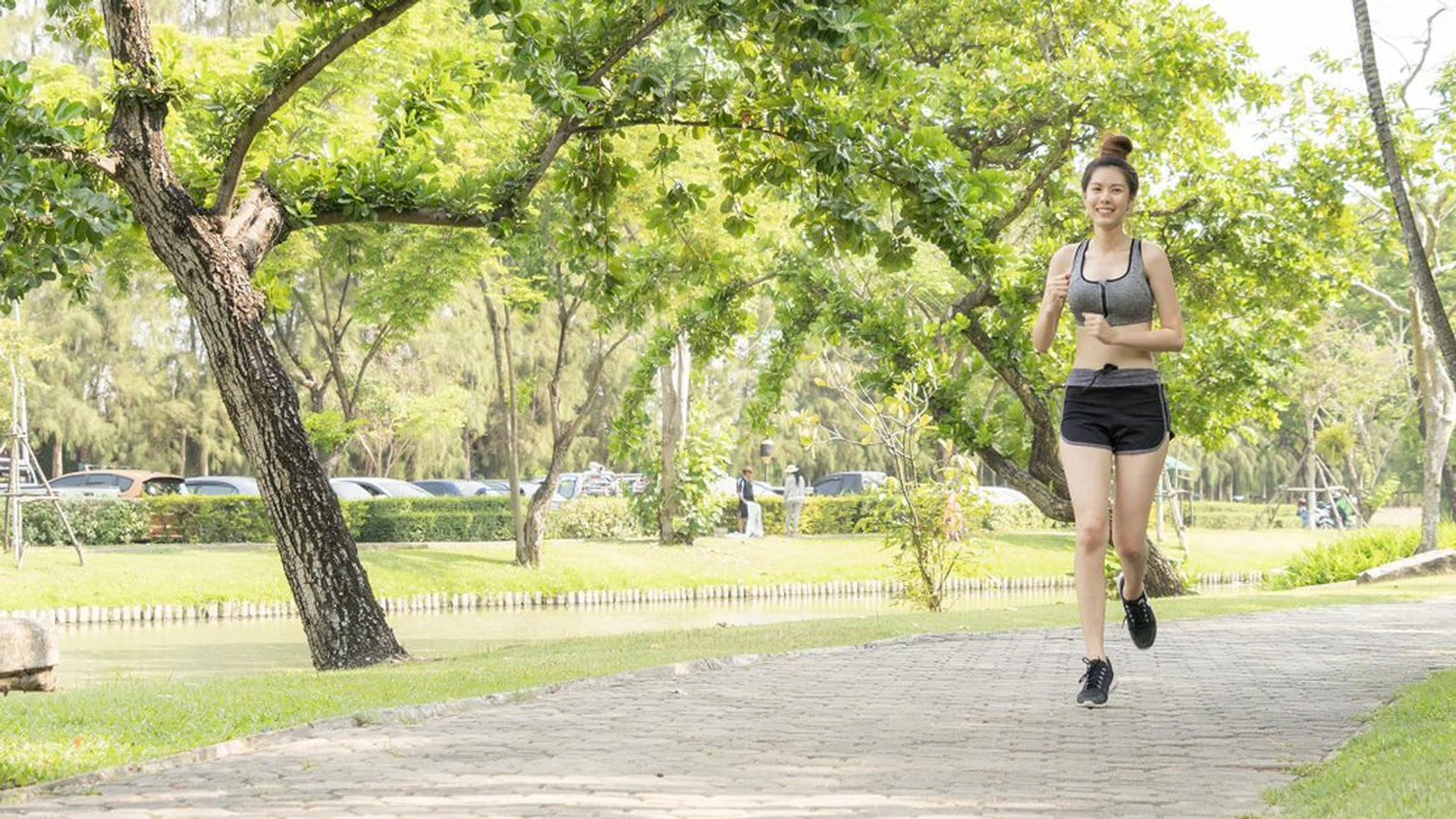 Asian pretty slim girl in fashion sportswear is running in public garden morning. Concept jogging outside in their towns and cities.
