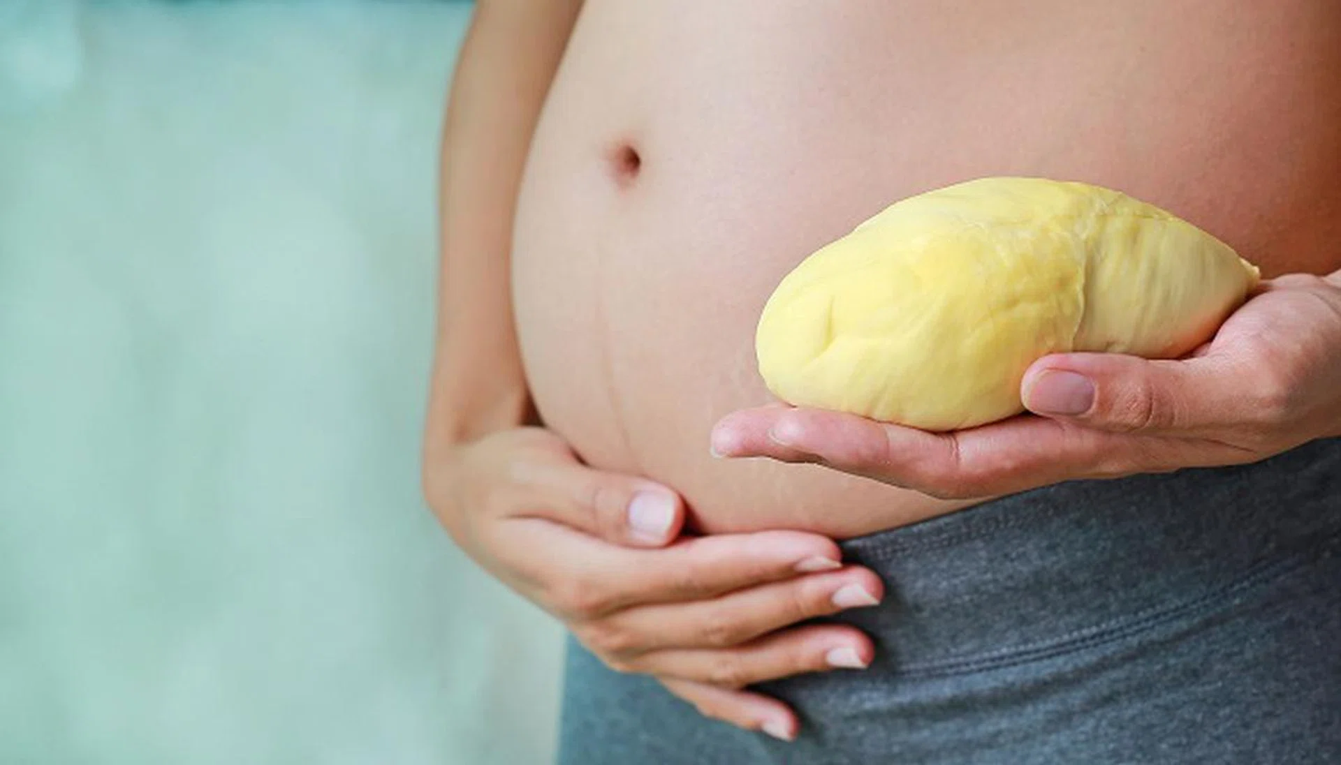 Pregnant woman holding durian at her belly. Dieting Concept.