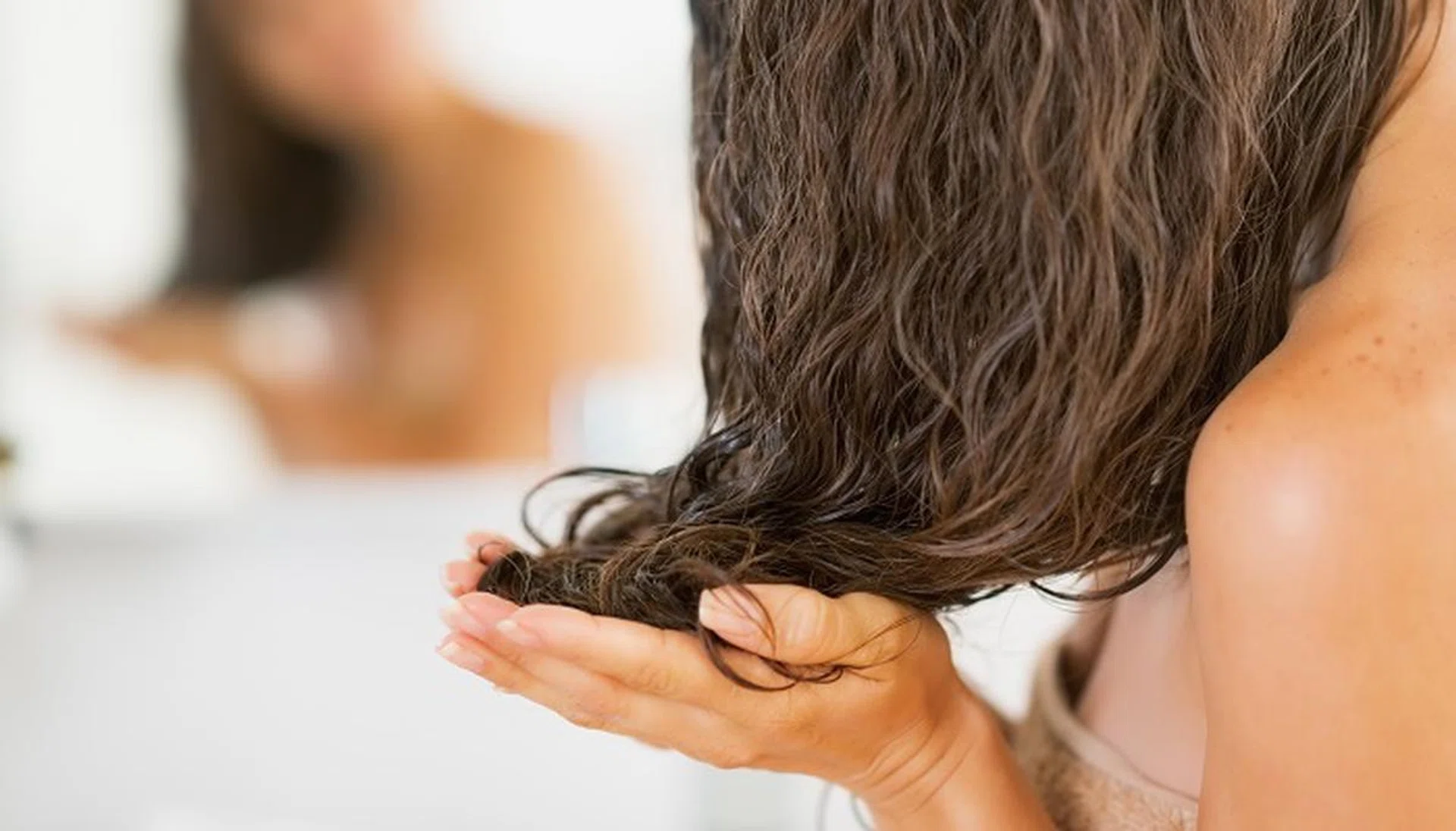 Closeup on young woman applying hair mask
