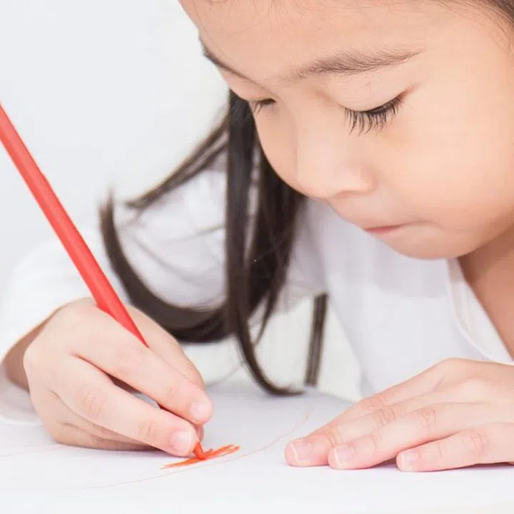 Education and school concept, little asian student girl drawing with pencils at school