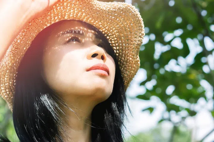 Asian woman in summer standing outdoors on sunny day with UV sunlight burning on skin face