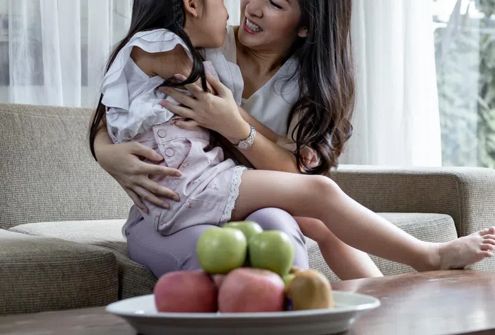 Asian mum and daughter do fun activities at the reception room. Mother and her daughter child girl playing together. Happy loving family concept.