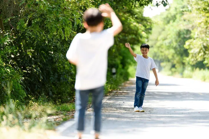 70905376 - two young thai boy walk and wave his hand in the park.
