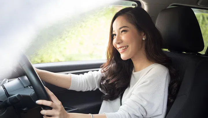 Asian women driving a car and smile happily with glad positive expression during the drive to travel journey, People enjoy laughing transport and relaxed happy woman on roadtrip vacation concept