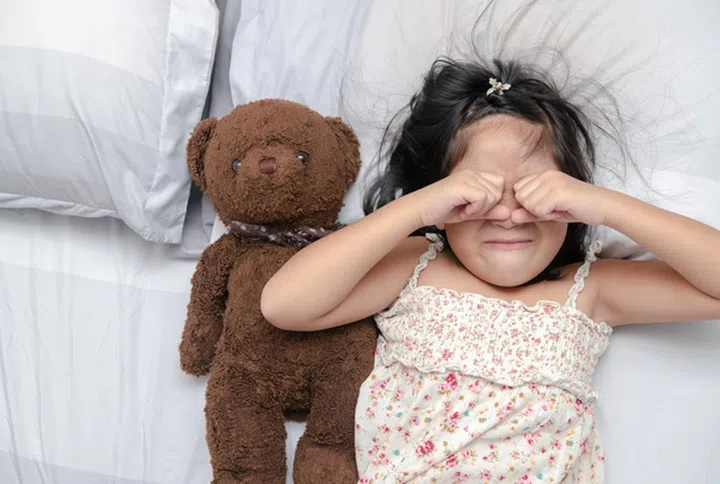 Little girl cry on bed with teddy bear on top view, emotion concept