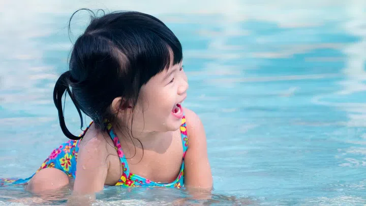 Happy asian kid laugh while playing in the swimming pool