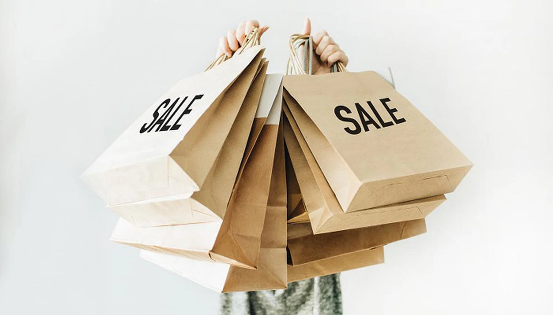 Black Friday sales discount concept. Young woman hold craft paper bags with word Sale on white background.