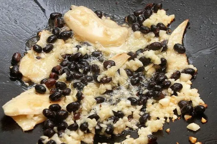 05. Heat 4 tbsps of oil in a wok or deep-frying pan. Fry the ginger for a minute. Add the garlic and fry until fragrant. Add the fermented black beans.