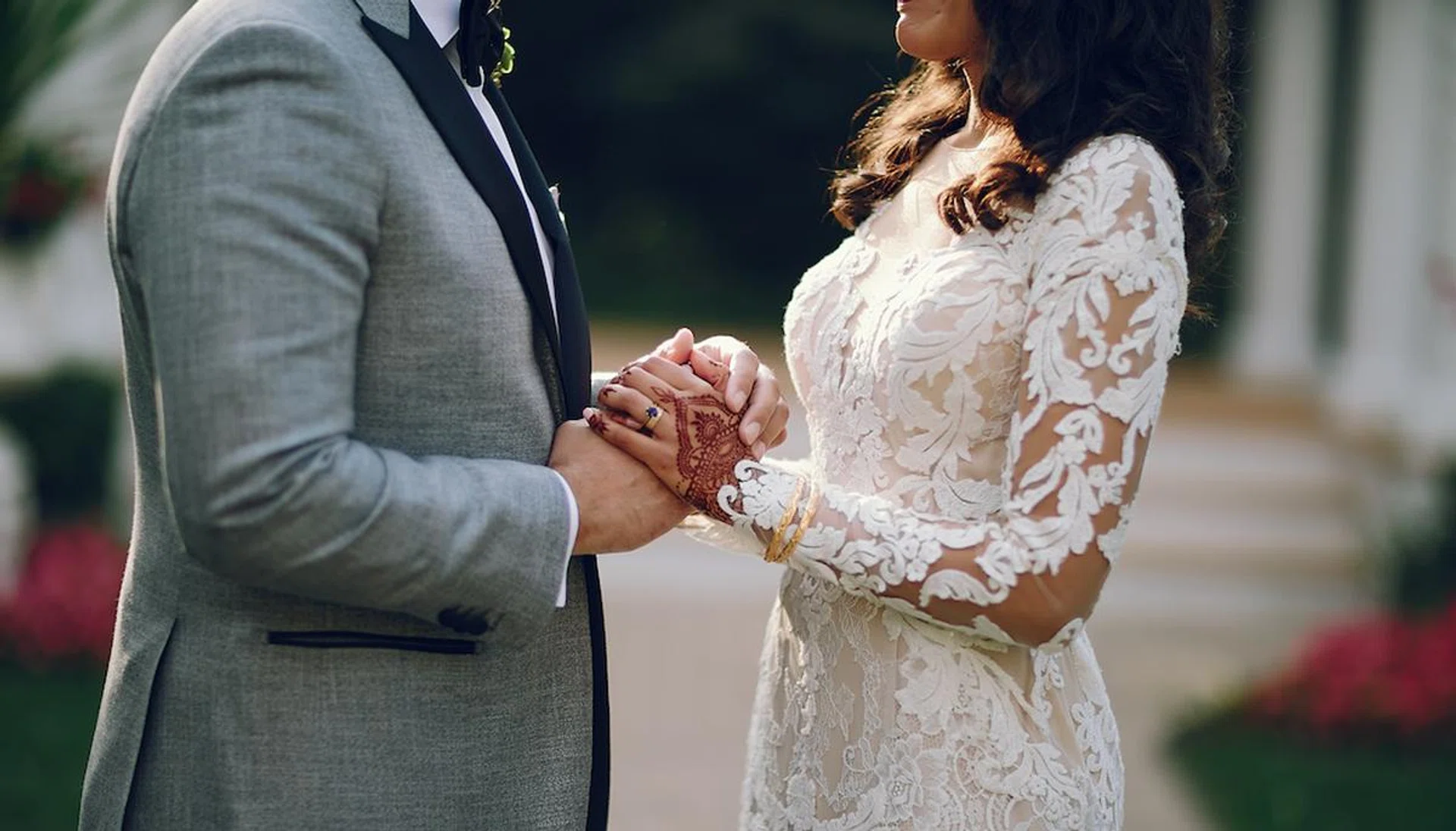 Beautiful bride with mehendi. Handsome fiance in a gray suit. Couple is holding hands