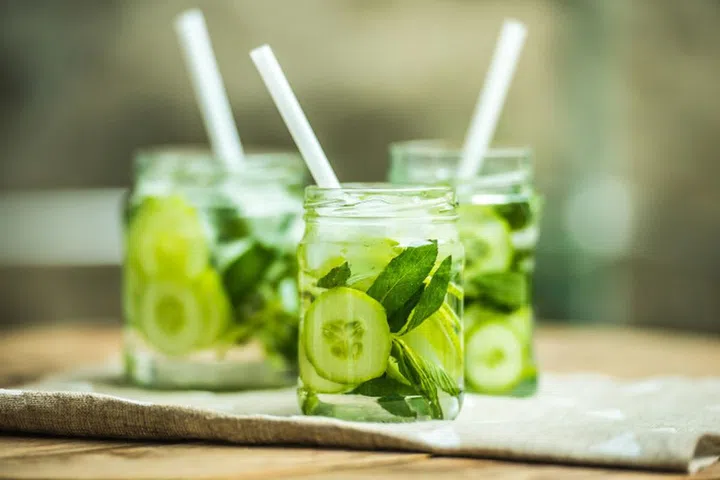 Three retro glass jars of lemonade with cucumber and mint on wooden table