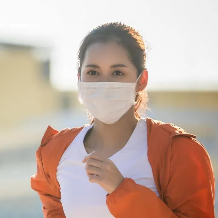 Asian Young fitness sport woman running  and she wears a mask for protective Dust and pollution and protection flu virus, influenza, coronavirus on city