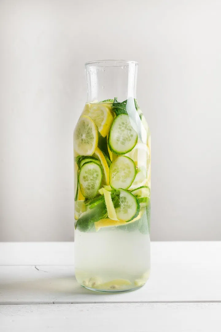 Sassy diet water. Cucumber, lemon, mint lemonade in glasses on white wooden table.