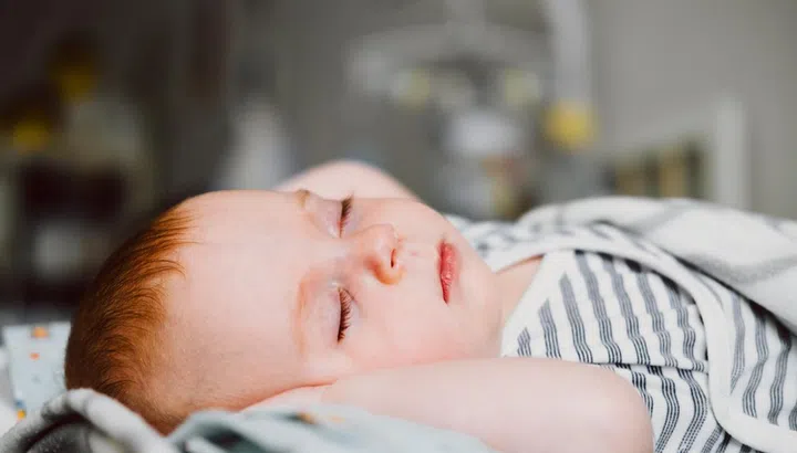 Cute little baby sleeping in a bed. Happy Family concept.