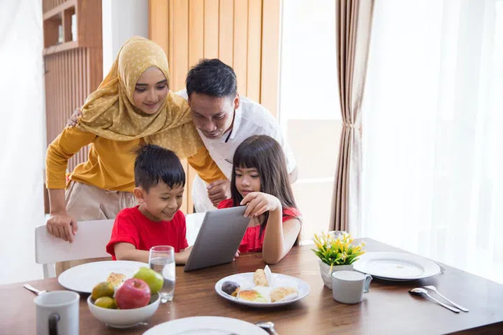 asian family using tablet pc at home during breakfast in the morning