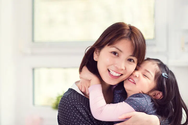 Portrait of happy japanese mother hugging with her cute little daughter at home