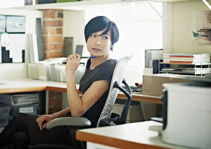 Female designer at desk in office head turned to look at computer