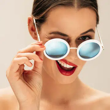 A woman, winks, hand on sunglasses, with groomed brows, lashes and nails, for a spa awards feature for The Singapore Women's Weekly.