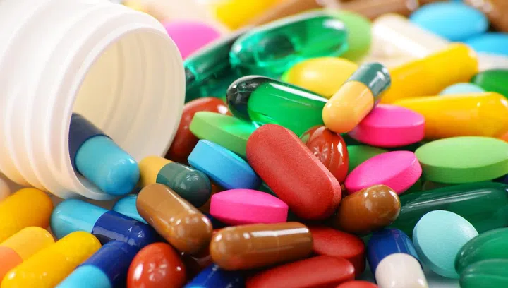 Composition with variety of drug pills and container.