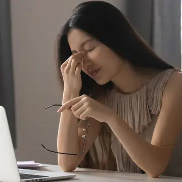Overworked stressed asian business woman holding glasses feeling eye strain