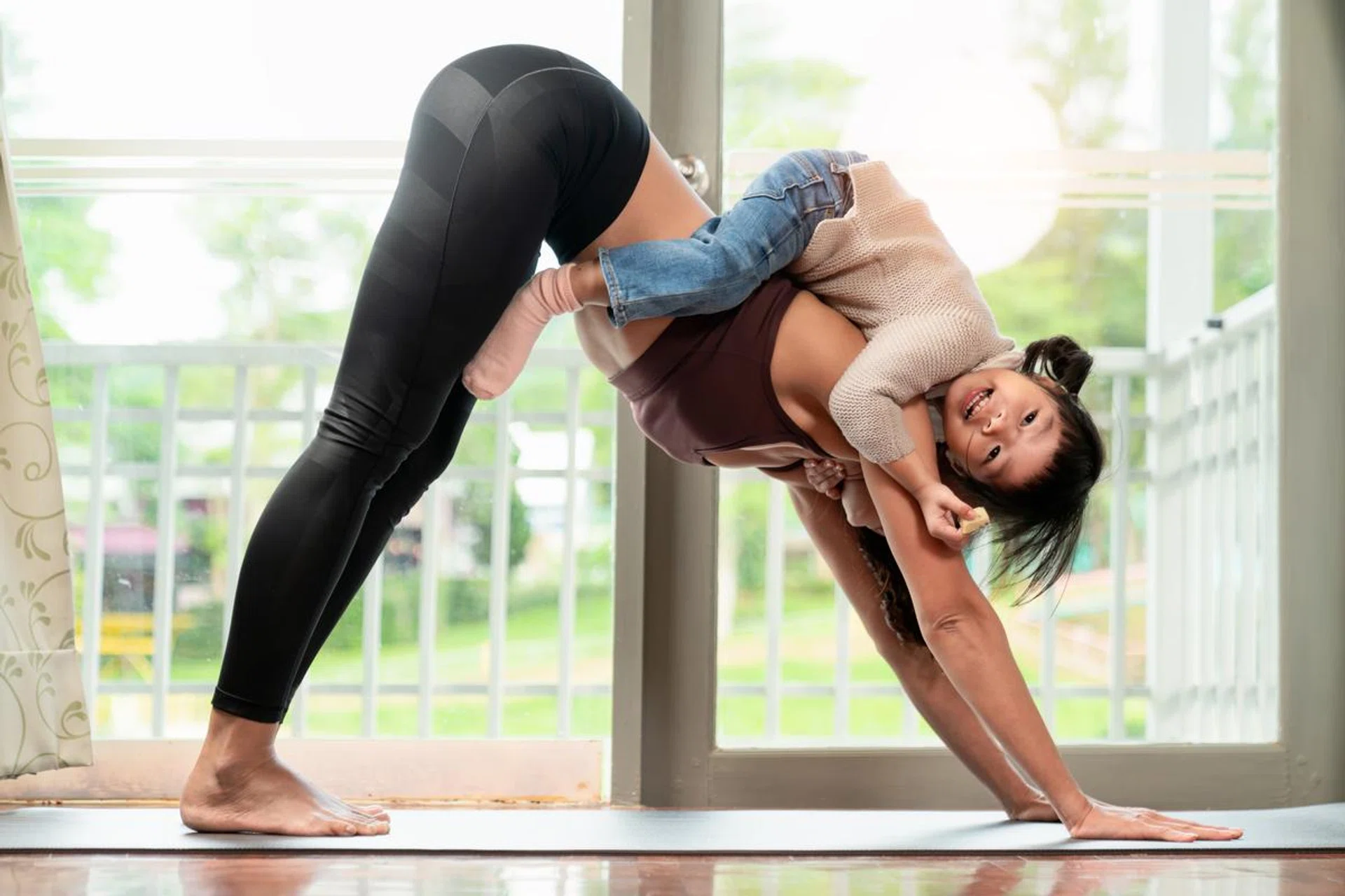 an Asian  female yoga instructor workout together with her daughter or son in the living room with window light on yoga met