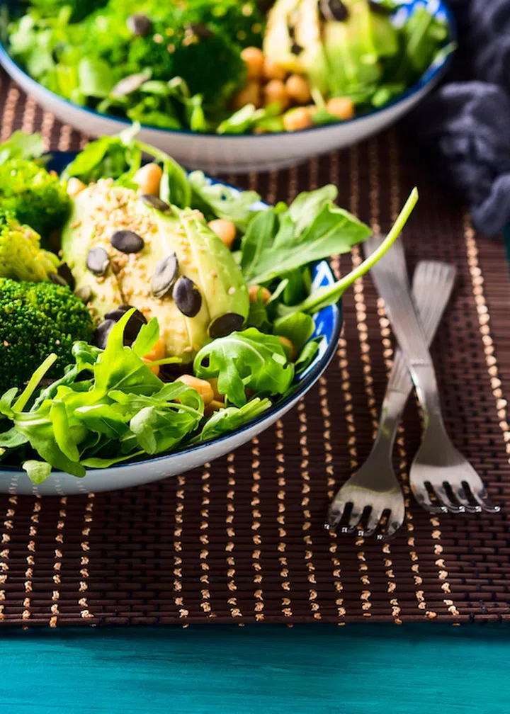 Green plant based salad with broccoli and avocado, arugula, pumpkin seeds, chickpeas. Vegan lunch bowl.