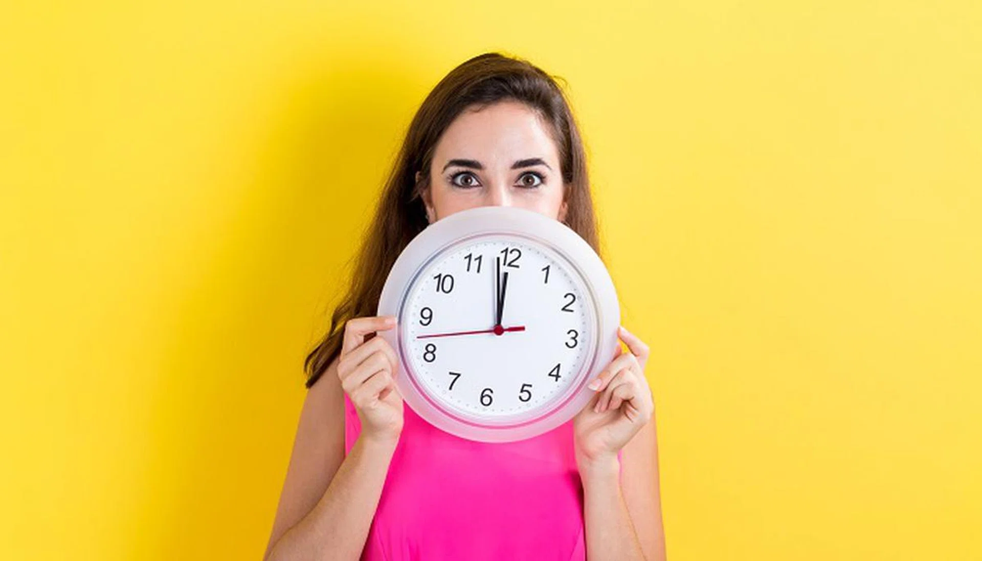 64984691 - woman holding a clock showing nearly 12