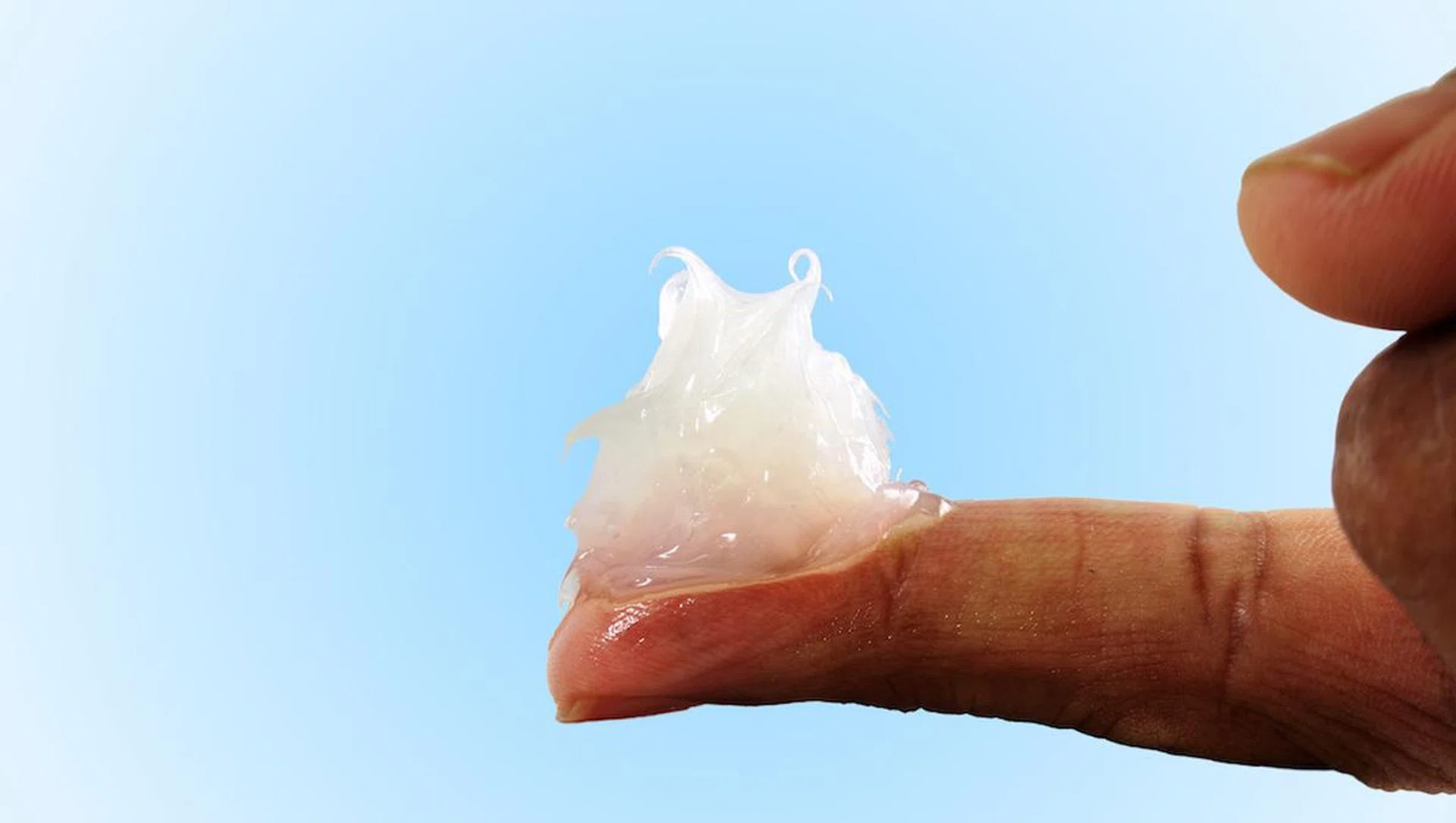 white petroleum jelly on finger in sky blue background