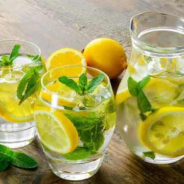 Lemonade in two glass and lemon with mint on the table