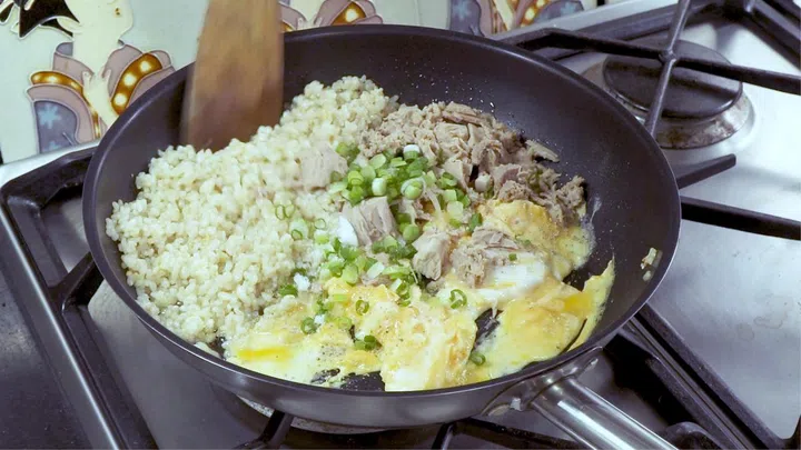 03. Push rice aside, add in beaten eggs. If your pan is not non-stick, you may need to add a little more oil. Add in drained tuna flakes, spring onion, salt and pepper. Stir to scramble the eggs.