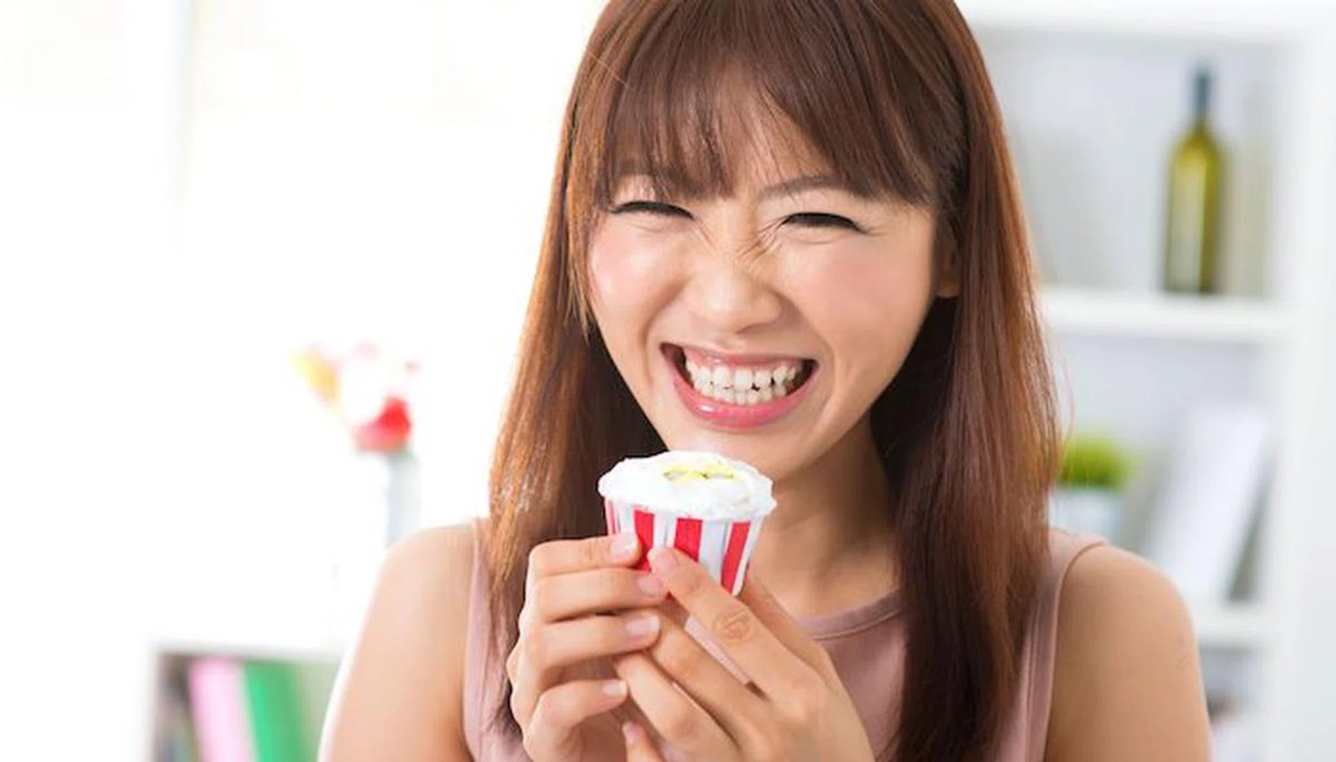 16380449 - young asian woman enjoying cupcake