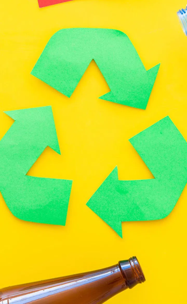 Waste for recycle and reuse near recycle symbol with arrows. Words paper, glass, plastic, cans on yellow background top view.