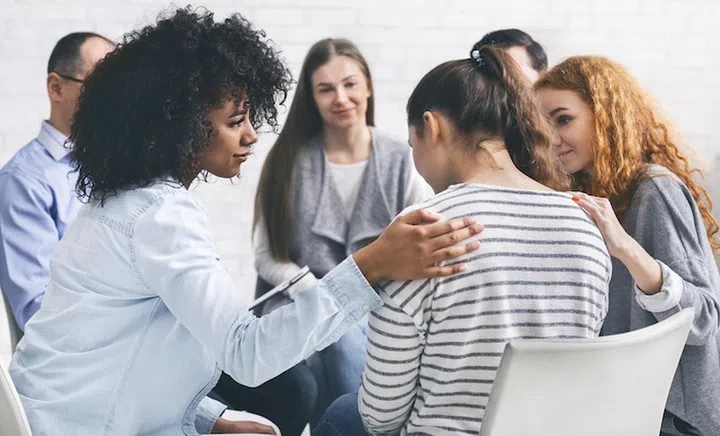 Support group. Addicted people comforting upset woman at psychotherapy session, free space