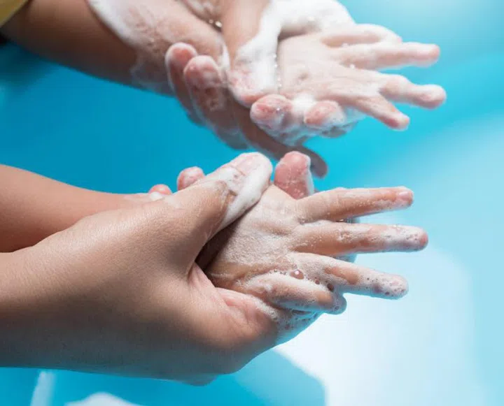 Mother and child washing hands with soap and water