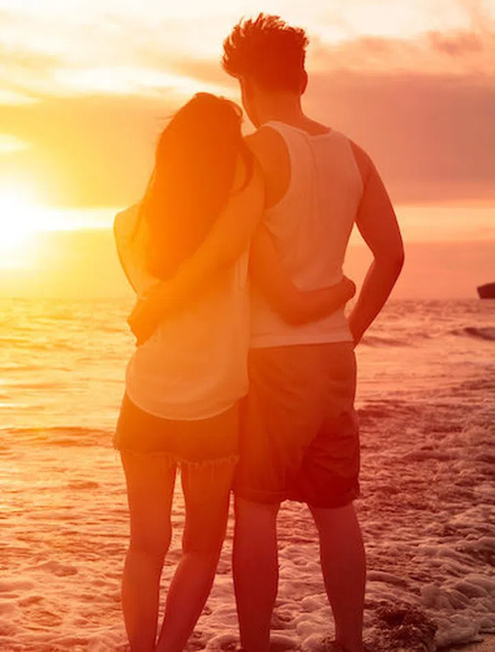 young couple watching sunset on the beach