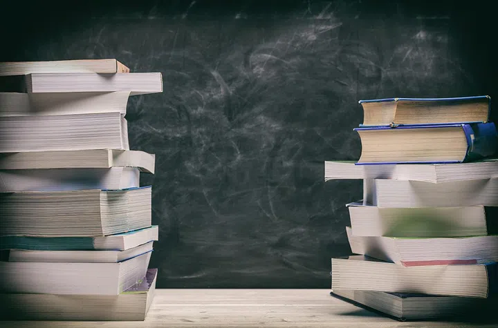 Back to school. Books stacked on black board background