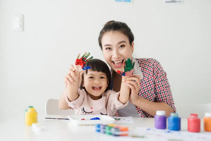 A happy family is painting. Mom help her daughter drawing