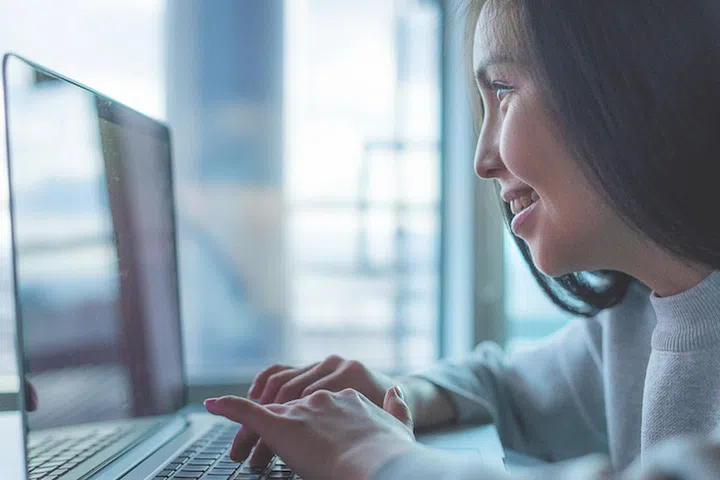 Young beautiful happy asian woman using laptop 