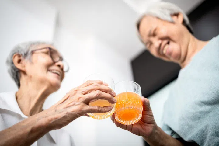 Healthy elderly sibling drinking vitamin C,orange juice and clinking glasses at home,senior people with effervescent vitamin C,strengthening the immunity for cold,flu,prevent the Coronavirus,Covid-19