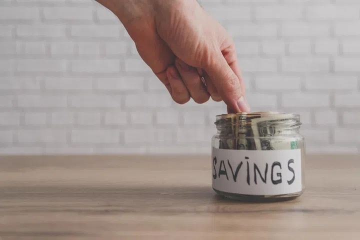 Money in glass jar on white background