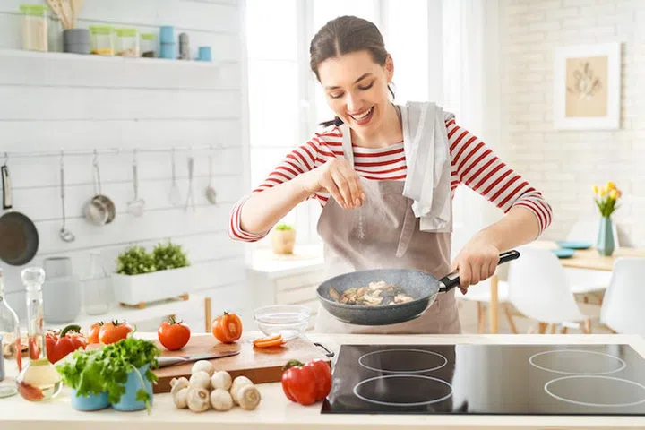 Healthy food at home. Happy woman is preparing the proper meal in the kitchen.