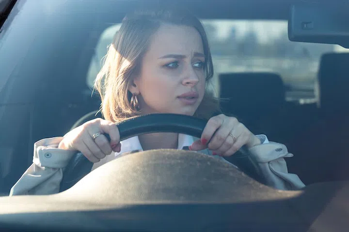 Woman drives her car for the first time, tries to avoid a car accident, is very nervous and scared, worries, clings tightly to the wheel. Inexperienced driver in stress and confusion after an accident