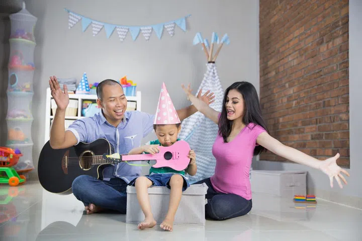 Happy family playing music and sing a long at home near a tent