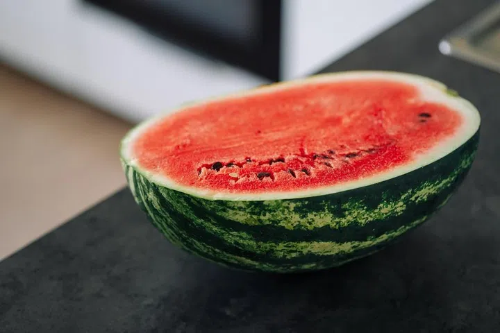 Half of fresh sliced watermelon on a kitchen table after the refrigerator. Authentic lifestyle. Home cooking, preparation of organic food.