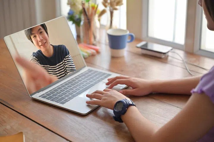 Young women use laptop for online video chat with male friend.