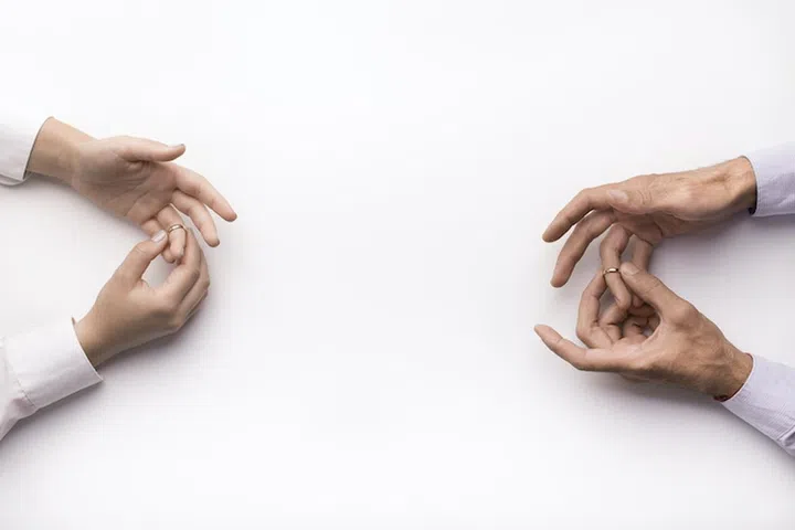 Husband and wife taking off an engagement rings, family conflict, family difficulties, divorce, white background, copy space