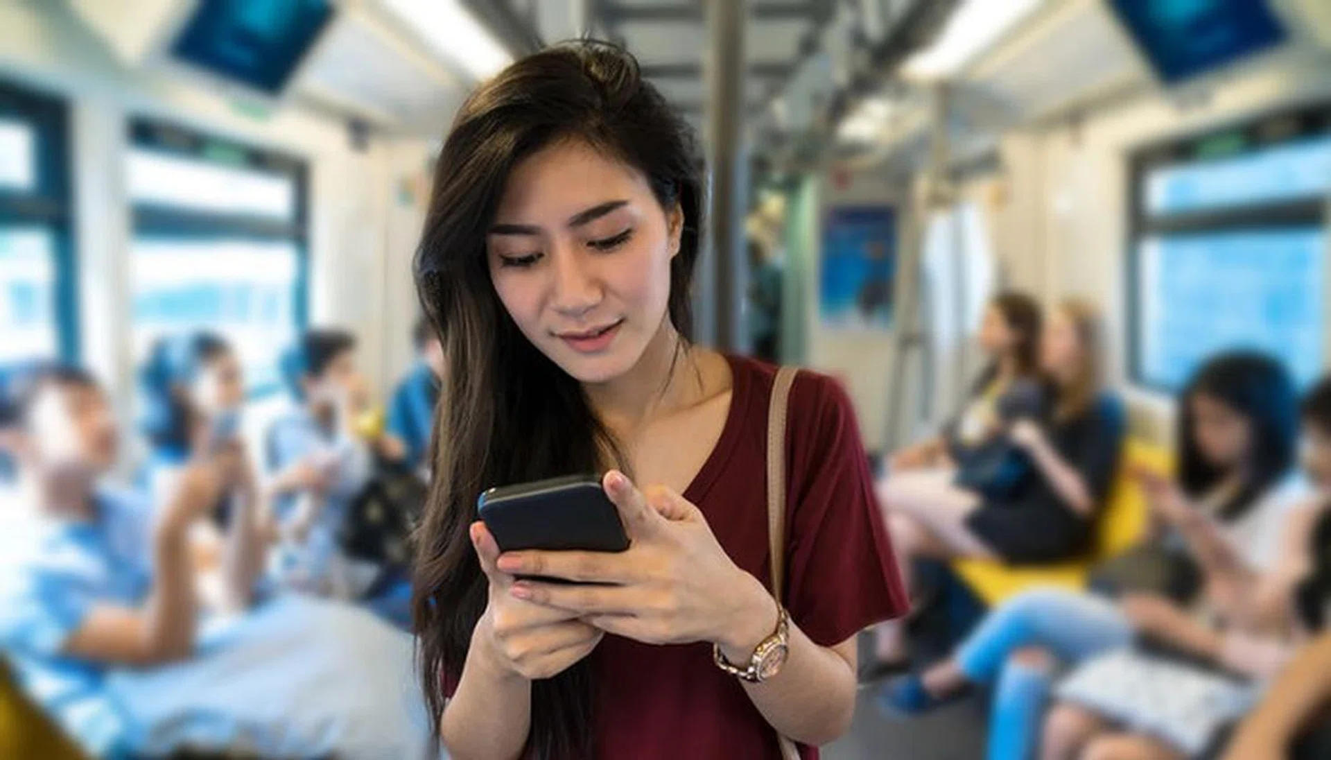 Asian woman passenger with casual suit using the social network via smart mobile phone in the BTS Skytrain rails or MRT subway for travel in the big city, lifestyle and transportation concept